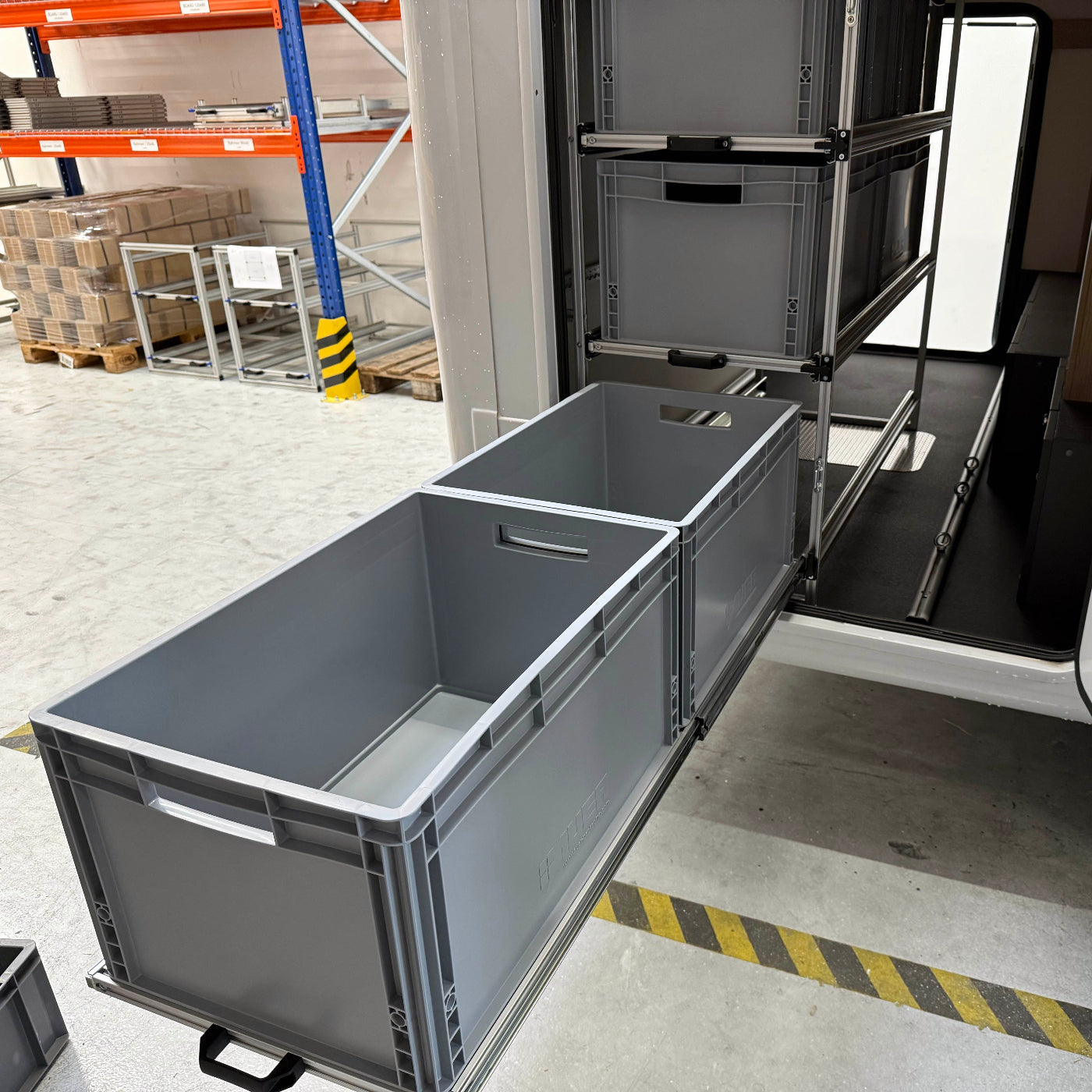 Heckgarage mit Wohnmobilregal, 3-stufig, geeignet für sechs Euroboxen, leicht zugänglich durch Schwerlastauszug. Eine Etage voll ausgezogen.